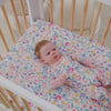 Baby in a crib with the Tiny Blooms Mini Crib Sheet