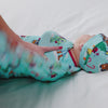 Adult dressing baby in the Disney & Pixar Christmas Village Swaddle & Hat Set