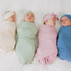 video of four children swaddled in Little Sleepies swaddle sets in Heather Oatmeal, Heather Sage, Heather Mauve, and Heather Blue