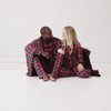 Video of two parents sitting on the ground with a Fireside Plaid Oversized Cloud Blanket® wrapped around them and wearing matching Fireside Plaid pajamas