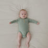 Newborn on a bed wearing the Willow Stripe Henley Bodysuit