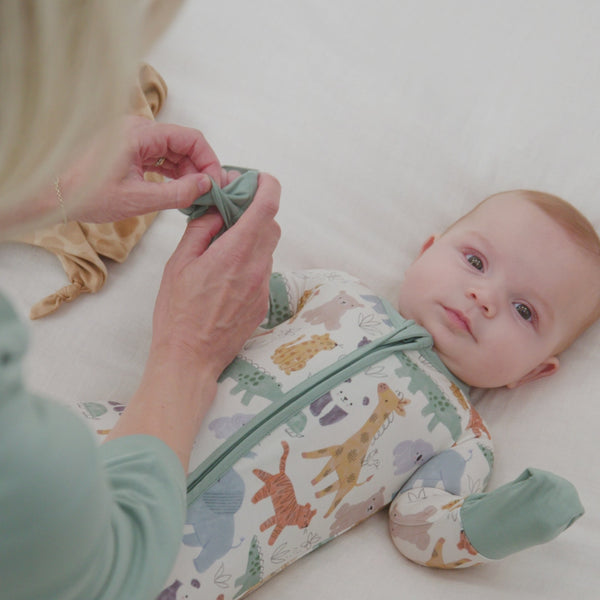 Baby laying on a bed wearing a Sweet Safari Zippy
