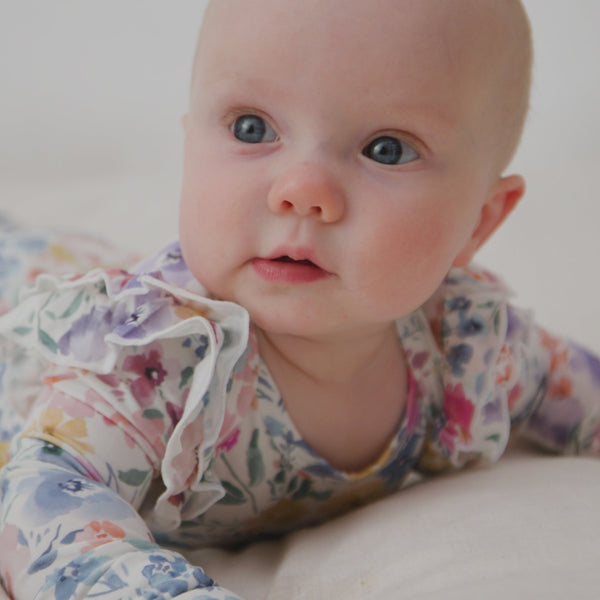 Baby on her tummy wearing the Tiny Blooms Flutter Bodysuit