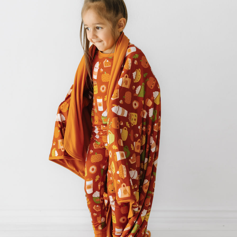 Side view image of a child wrapped up in a Pumpkin Spice large cloud blanket