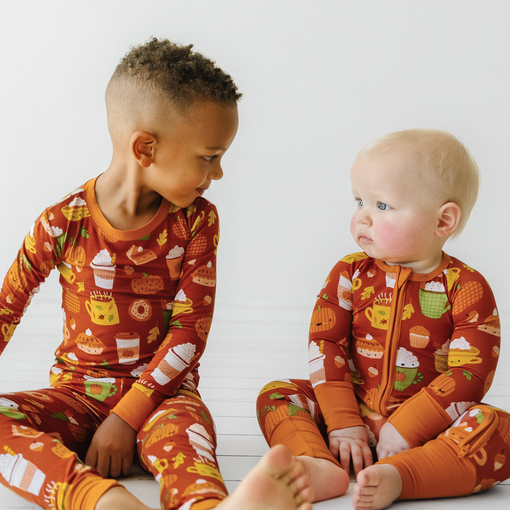 Two children sitting on the ground wearing matching Pumpkin Spice pajamas