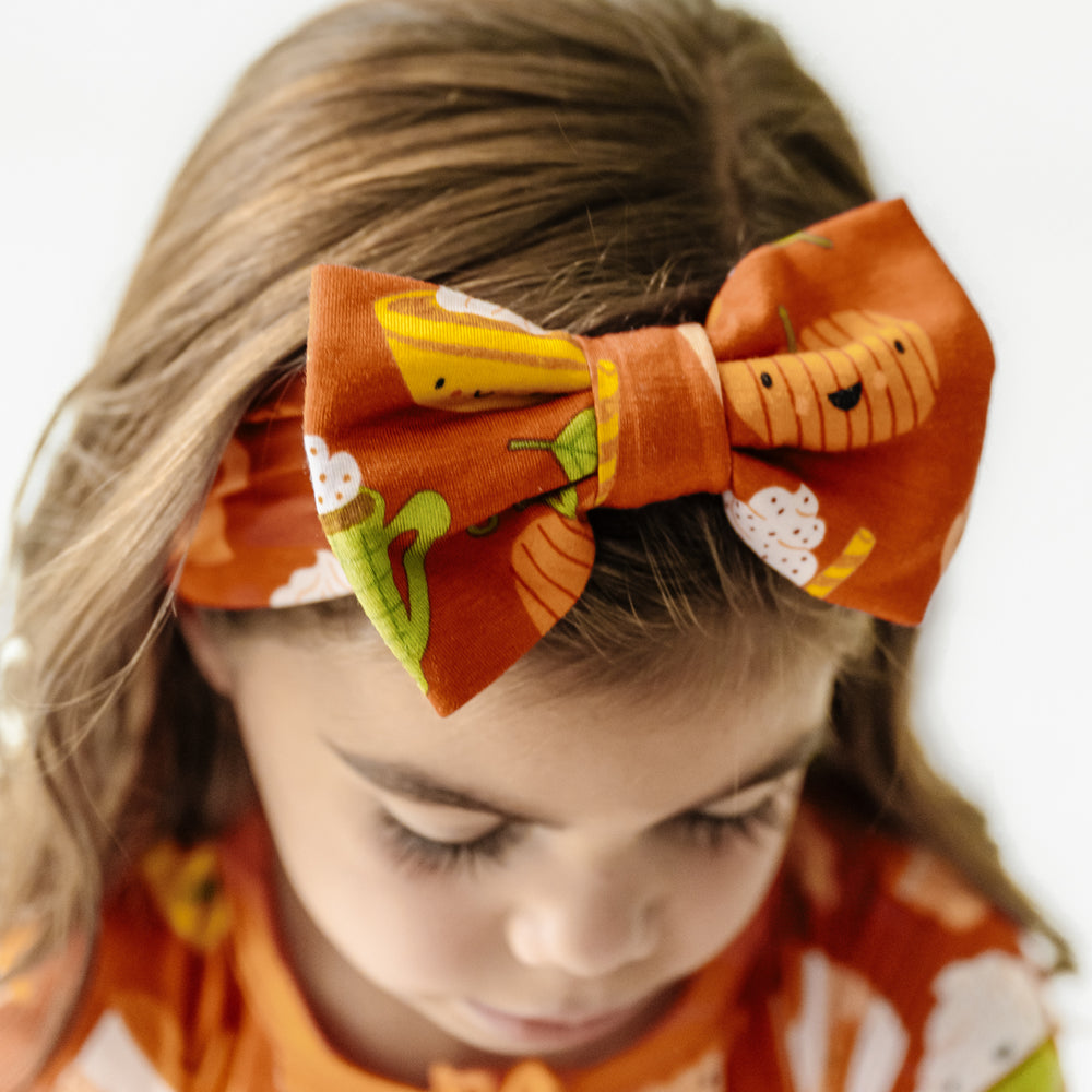 Close up image of a child wearing a Pumpkin Spice luxe bow headband