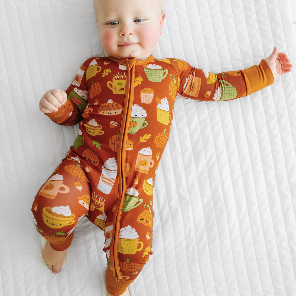Child laying on a bed wearing a Pumpkin Spice zippy