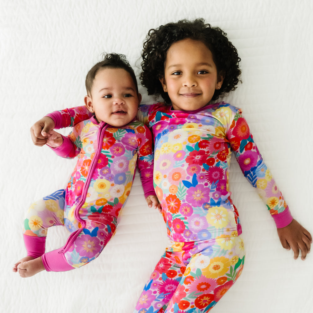 Two children laying on a blanket wearing matching Rainbow Blooms pajamas