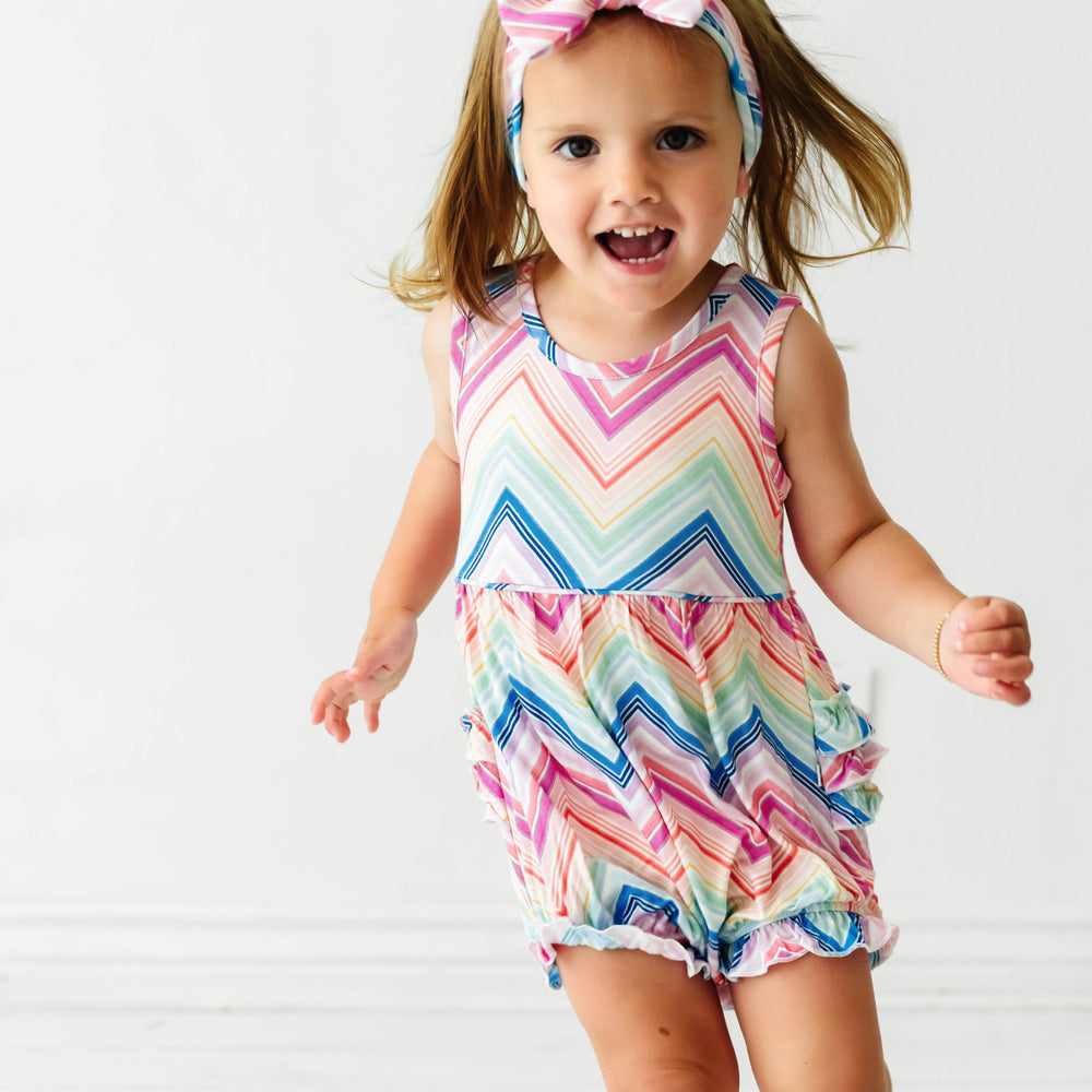 Child jumping wearing a Rainbow Chevron printed bubble romper