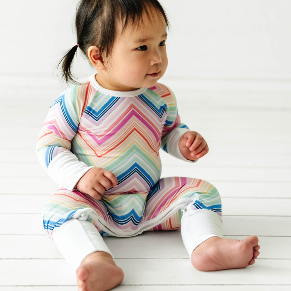 Click to see full screen - Alternate image of child sitting down wearing a Rainbow Chevron printed crescent zippy