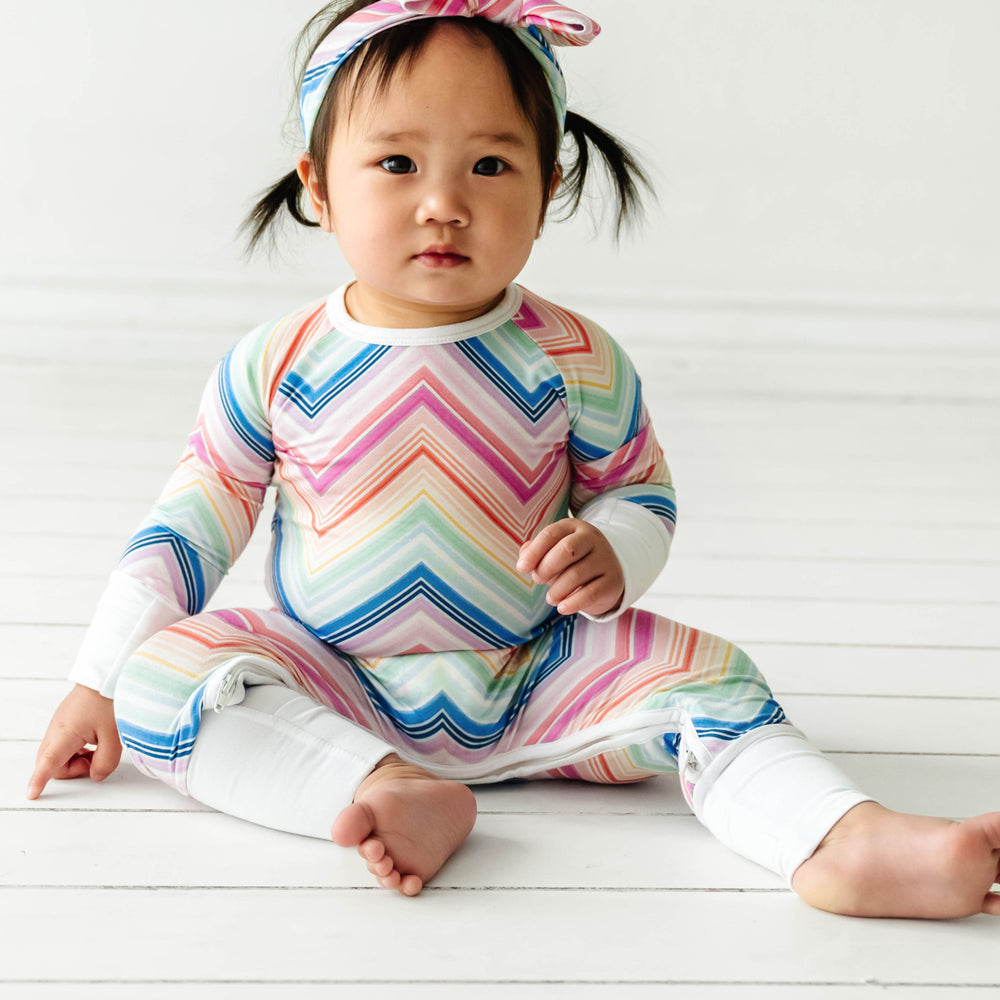 Click to see full screen - Child sitting down wearing Rainbow Chevron printed crescent zippy
