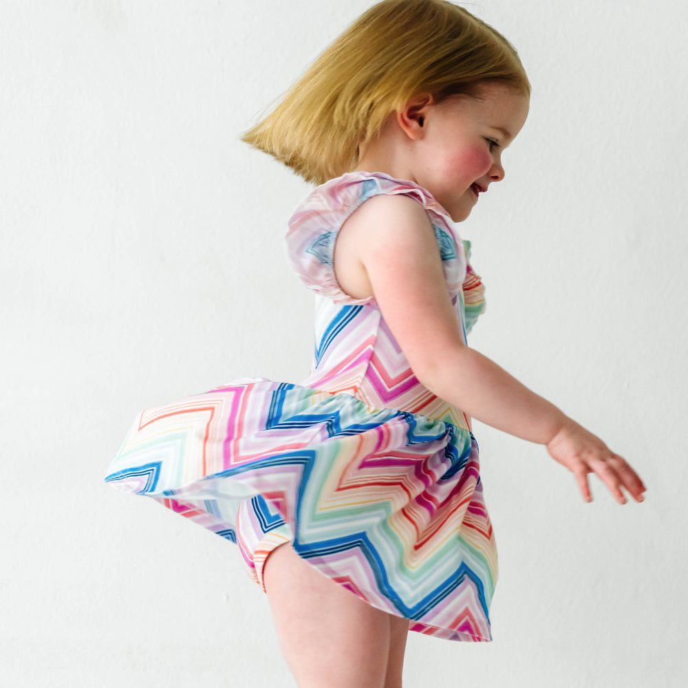 Child spinning around wearing a Rainbow Chevron printed flutter sleeve skater dress with bodysuit