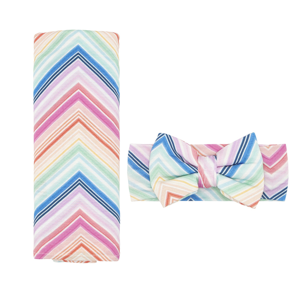 Flat lay image of a Rainbow Chevron printed swaddle and luxe bow set