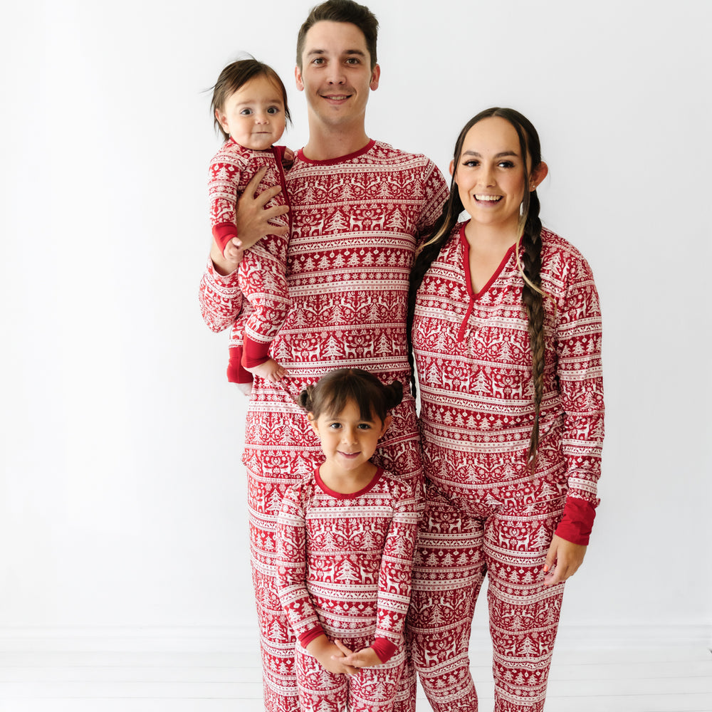 Family of four wearing matching Reindeer Cheer pajamas. Mom is wearing Reindeer Cheer's women's pajama top and pants. Dad is wearing men's Reindeer Cheer pajama pants and matching top. Children are wearing matching pjs in zippy and two piece styles.