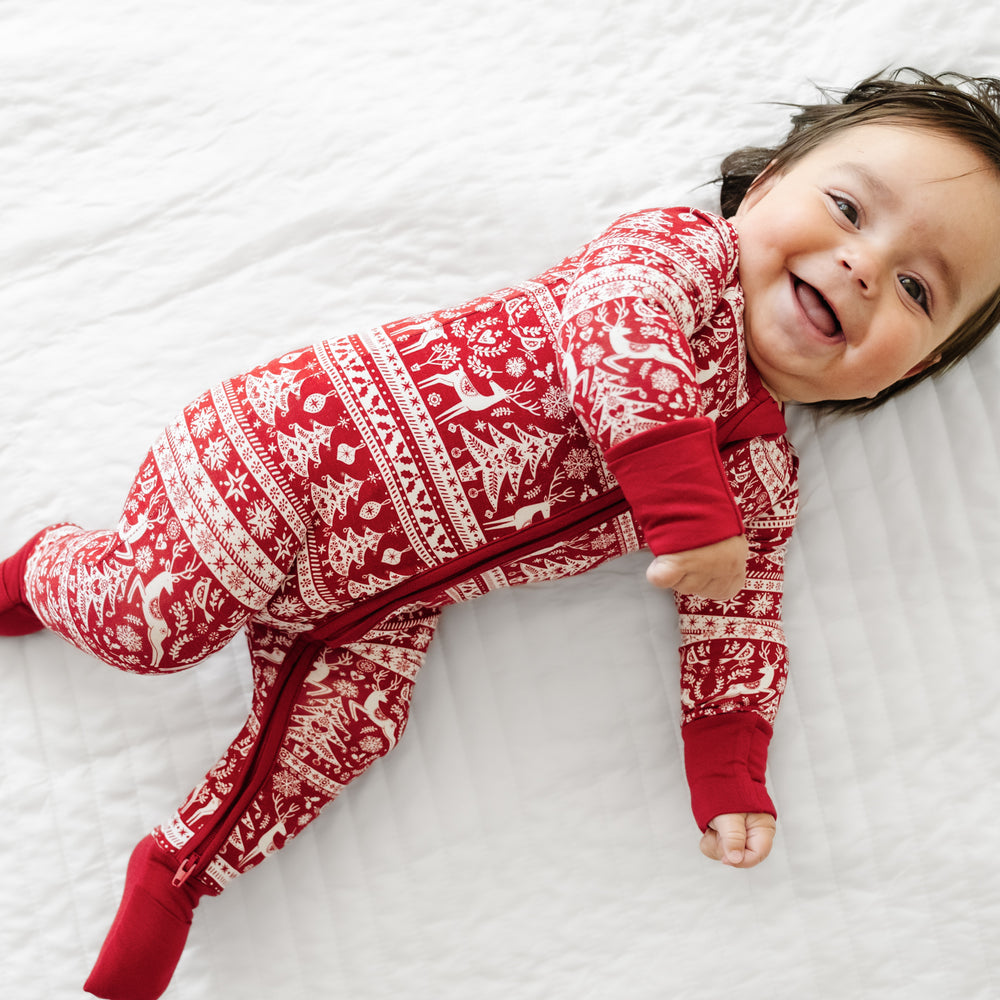 Side view of a child laying on a bed wearing a Reindeer Cheer zippy