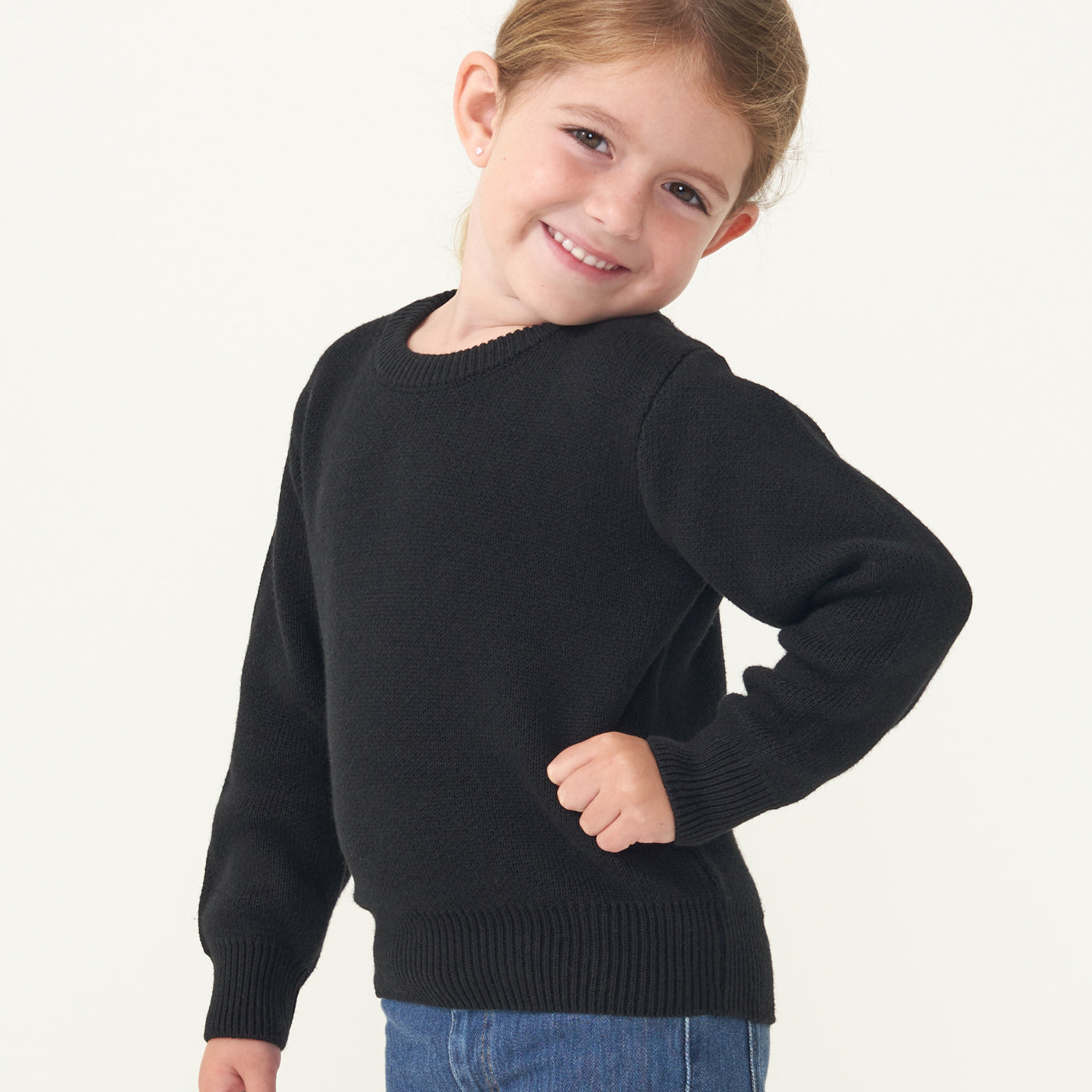 Child with her hand on her hip wearing a Black knit sweater