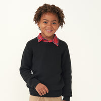 Child wearing a Black knit sweater and coordinating Holiday Plaid polo shirt