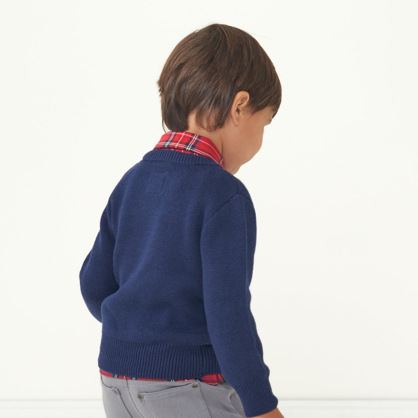 Back view image of a child wearing a Classic Navy knit sweater and coordinating Holiday Plaid polo shirt