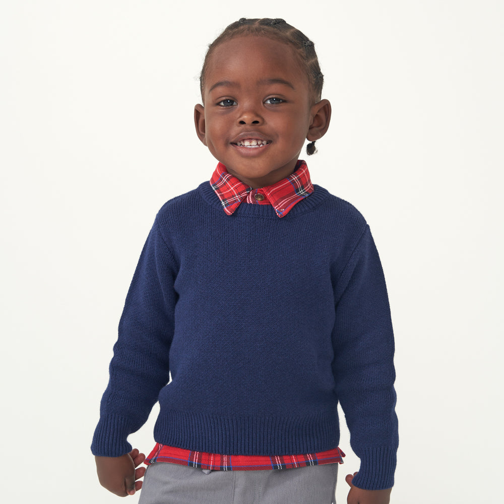 Close up image of a child wearing a Classic Navy knit sweater and coordinating Holiday Plaid polo shirt