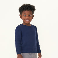Child turned to the side wearing a Classic Navy knit sweater