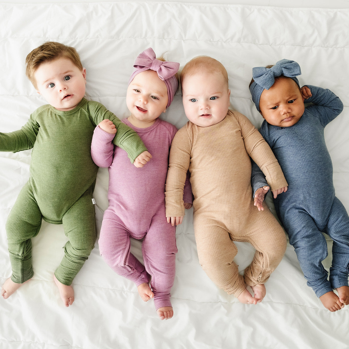 Four Children in coordinating Winter Heathered Solids crescent zippies in the following colors: Heather Cypress Green, Heather Mulberry, Heather Fawn, and Heather Dusty Indigo paired with matching luxe bow headbands