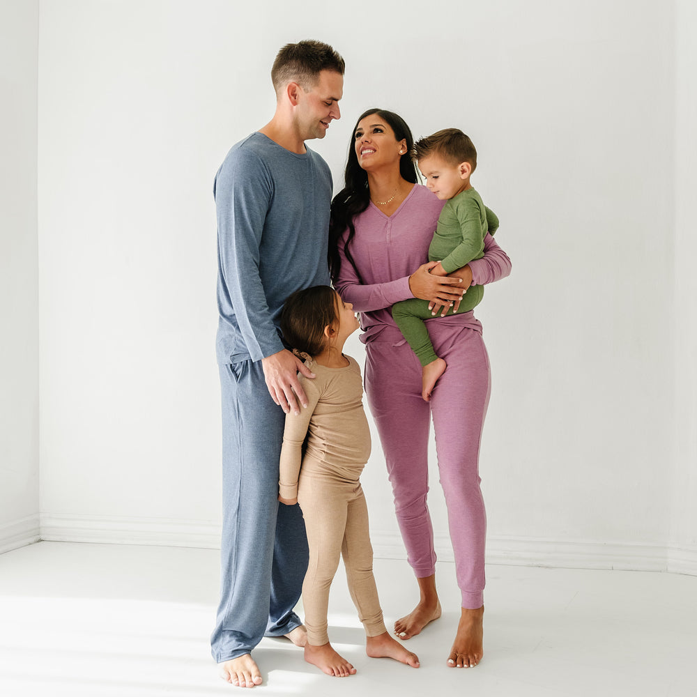 Family of four wearing coordinating Heather Ribbed pajamas. Dad is wearing Heather Dusty Indigo Ribbed men'a pajama top paired with men's pajama pants. Mom is wearing Heather Mulberry women's pj top paired with matching women's pj pants. Children are wearing Heather Fawn Ribbed and Heather Cypress Ribbed two piece pj sets