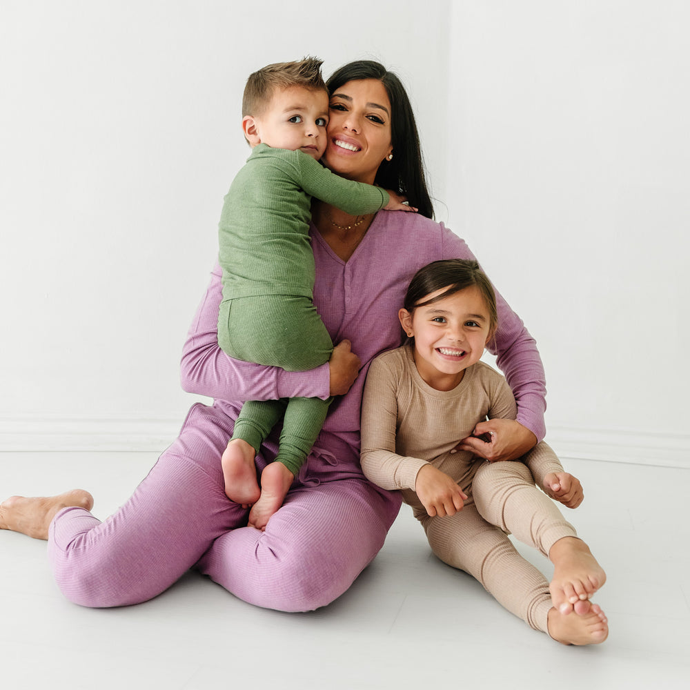 Mother and her two children. Mom is wearing Heather Mulberry Ribbed women's pajama top and pants. Her children are wearing two piece pajamas in Heather Cypress Ribbed and Heather Fawn Ribbed colors