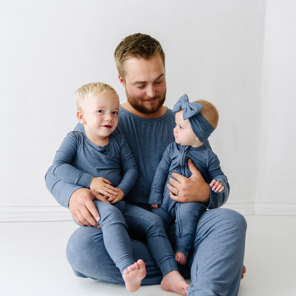 Father and his two children wearing matching Heather Dusty Indigo Ribbed pajama sets paired with a matching luxe bow headband
