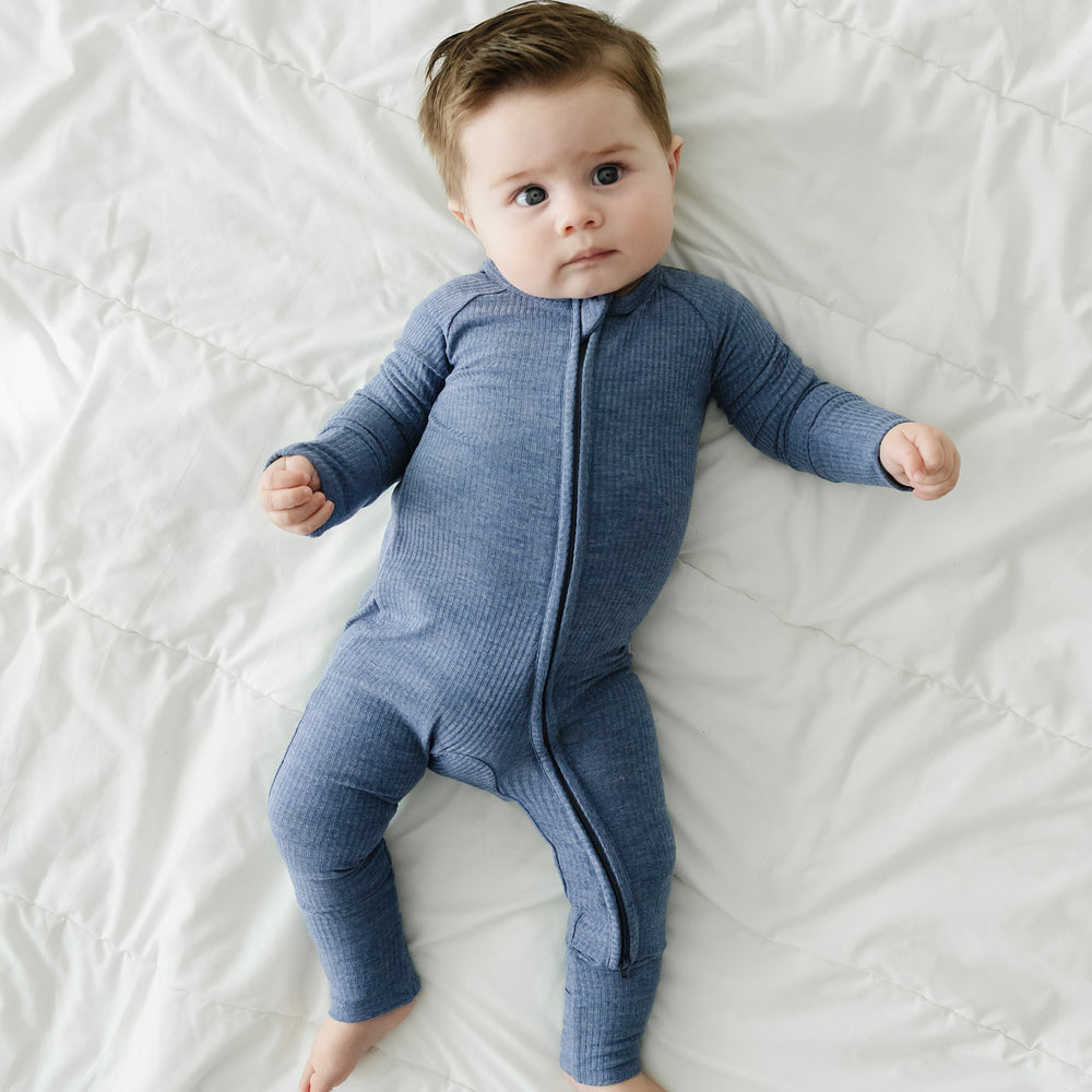 Child laying on a bed wearing a Heather Dusty Indigo Ribbed zippy