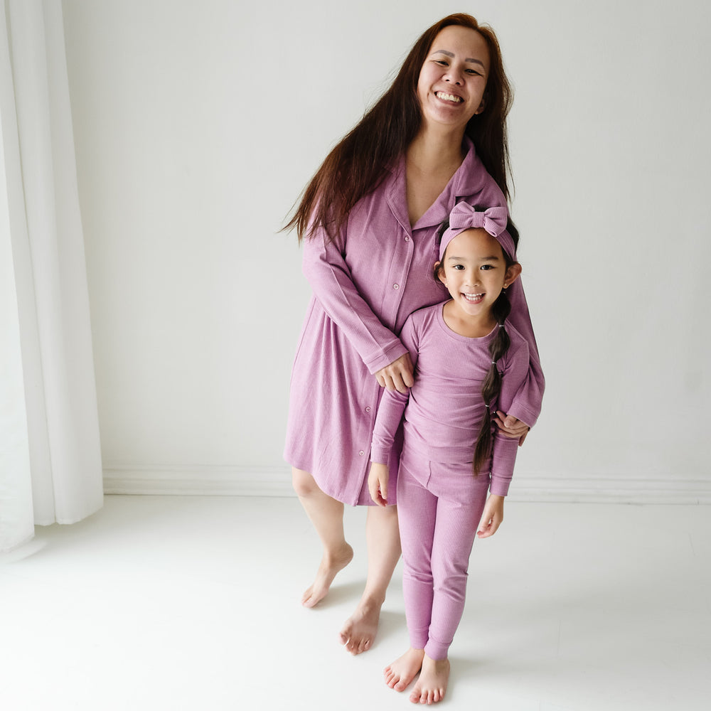 Mother and child matching in Heather Mulberry ribbed pjs. Mom is wearing a Heather Mulberry Ribbed women's sleep shirt and daughter is wearing a matching two piece pajama set paired with a matching luxe bow headband