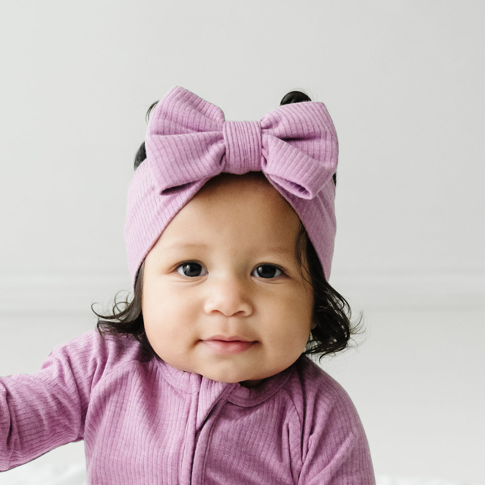 alternative close up image of a child wearing a Heather Mulberry ribbed luxe bow headband paired with a matching zippy