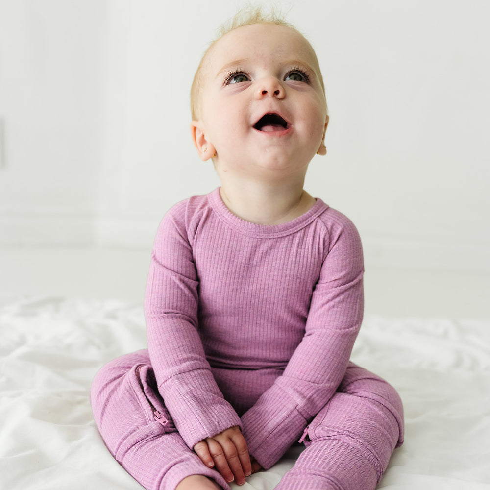 Child sitting on a blanket wearing a Heather Mulberry Ribbed Crescent Zippy