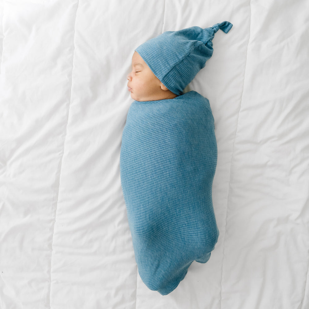 Child swaddled in a Heather Blue Ribbed swaddle and hat set