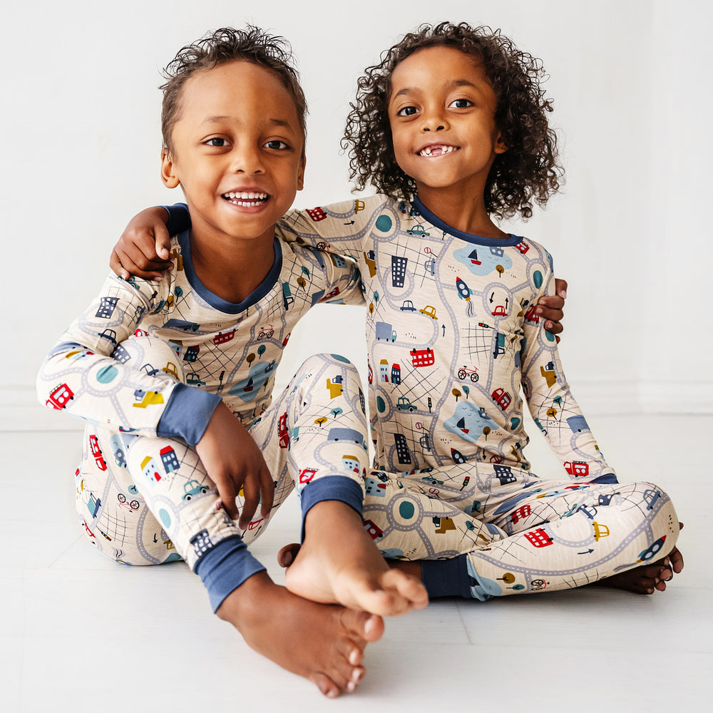 Click to see full screen - Two children sitting wearing Blue Road Trip two piece pajama sets