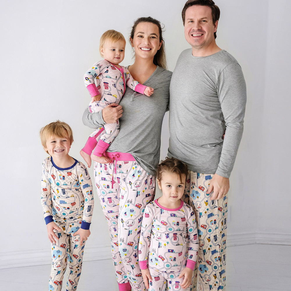 Family of five wearing matching Road Trip pajama sets. Dad is wearing Men's blue Road Trip pajama pants paired with a Heather Gray men's pajama top. Mom is wearing Rosy Road Trip women's pajama pants paired with a Heather Gray women's pajama top. Kids are wearing Blue and Rosy Road trip pjs in two piece and zippy styles