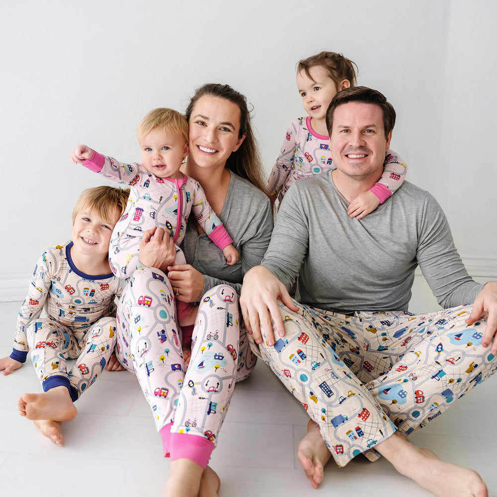 Click to see full screen - Family of five sitting wearing matching Road Trip pajama sets. Dad is wearing Men's blue Road Trip pajama pants paired with a Heather Gray men's pajama top. Mom is wearing Rosy Road Trip women's pajama pants paired with a Heather Gray women's pajama top. Kids are wearing Blue and Rosy Road trip pjs in two piece and zippy styles