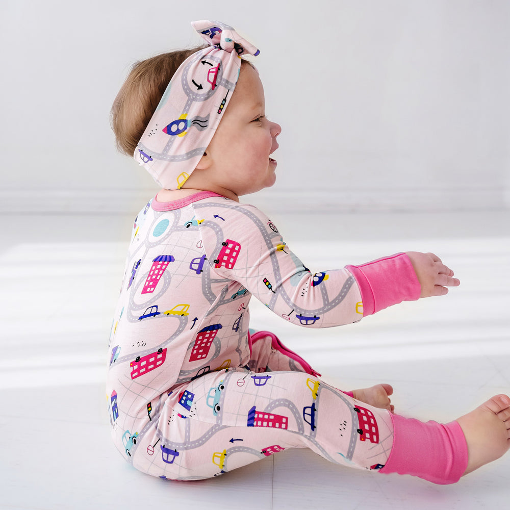 Click to see full screen - Profile view of a child wearing a Rosy Road Trip luxe bow headband and matching zippy