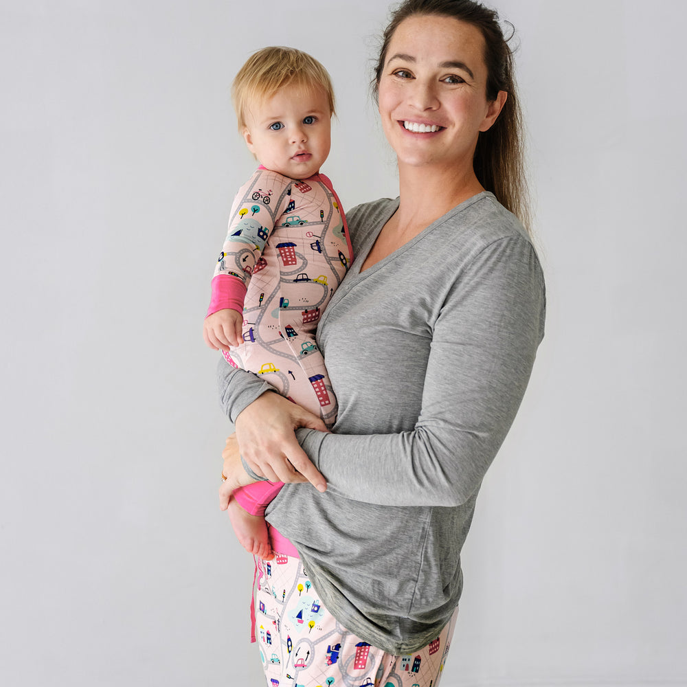 Click to see full screen - Mother holding her child wearing matching Rosy Road Trip pajamas. Mom is wearing women's Heather Gray women's pajama top and coordinating Rosy Road Trip women's pj pants. Child is matching wearing a Rosy Road Trip zippy