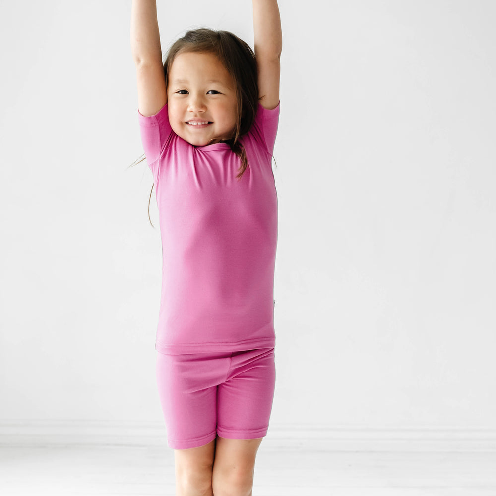 Click to see full screen - Child stretching wearing a Rosette two piece short sleeve and shorts pajama set