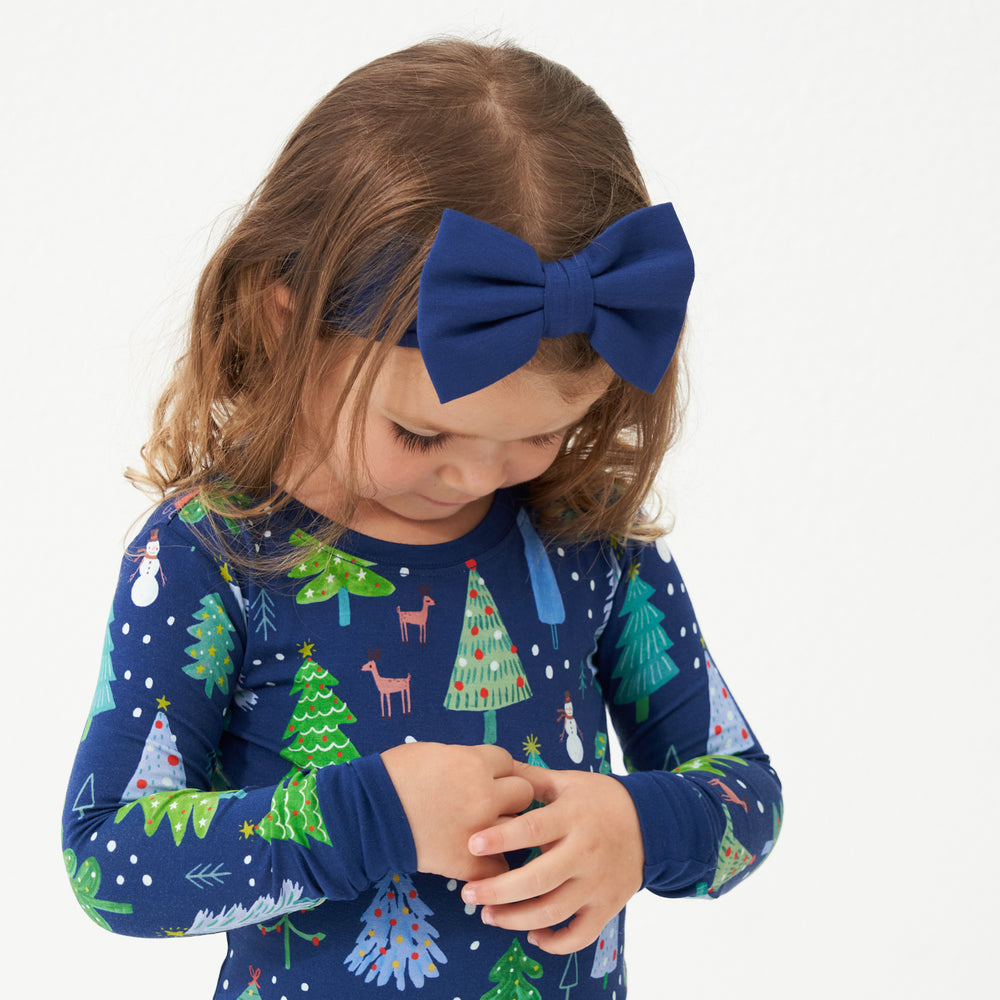 Child wearing a Sapphire luxe bow headband with a Blue Merry and Bright two piece pajama set