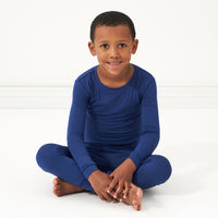 Child sitting wearing a Sapphire two piece pajama set