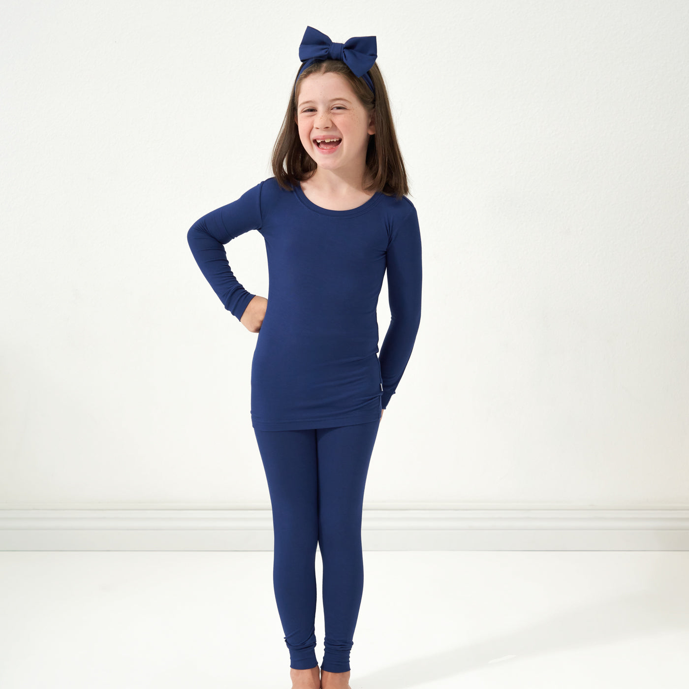 Child posing wearing a Sapphire two piece pajama set paired with a matching luxe bow headband