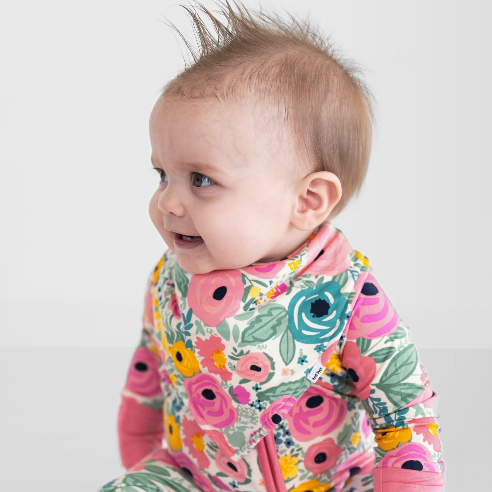 Child looking to the side wearing a Secret Garden baby bandana bib over matching bamboo pajamas