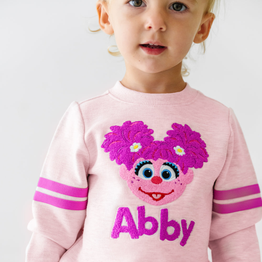 Close up image of a child wearing a Sesame Street Abby crewneck