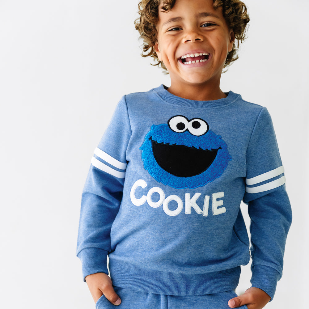 Close up image of a child wearing a Sesame Street Cookie Monster crewneck sweatshirt and jogger set