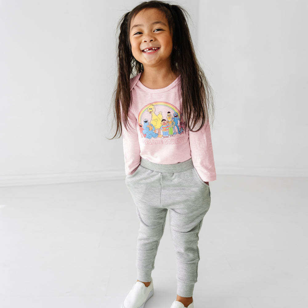 Child wearing a Sesame Street pink graphic bodysuit and Heather Gray joggers