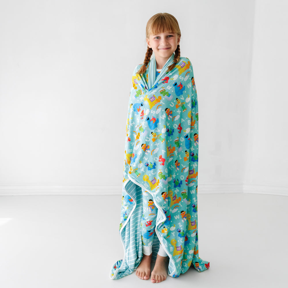 Child wrapped up in a Spelling with Sesame Street large cloud blanket