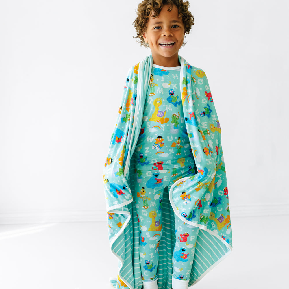 Child laughing wrapped up in a Spelling with Sesame Street large cloud blanket