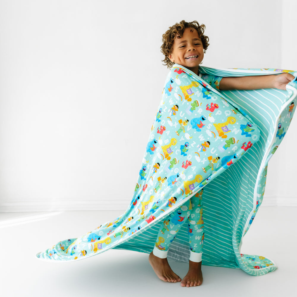 Child spinning and wrapped up in a Spelling with Sesame Street large cloud blanket