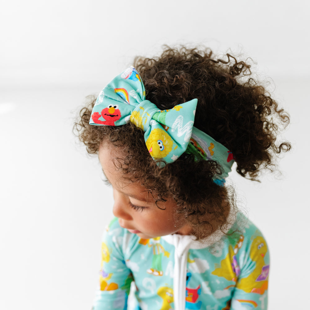Overhead shot of a child wearing a Spelling with Sesame Street luxe bow headband
